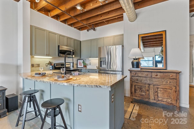 kitchen with stainless steel appliances, sink, kitchen peninsula, backsplash, and light stone countertops