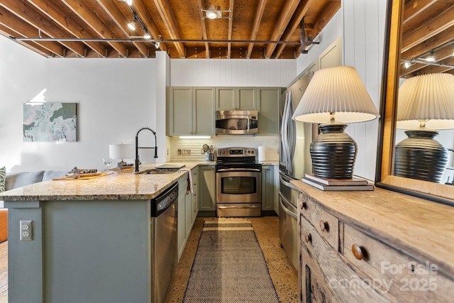 kitchen featuring stainless steel appliances, sink, backsplash, and light stone counters