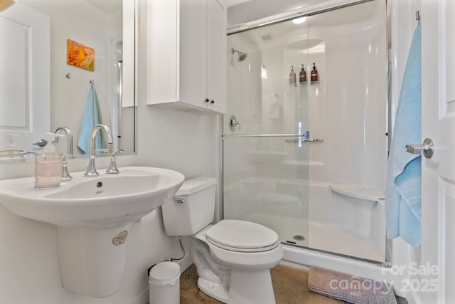 bathroom with toilet, a shower with door, and sink