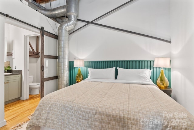 bedroom featuring light hardwood / wood-style flooring and ensuite bathroom