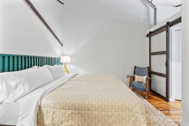 bedroom featuring a barn door and wood-type flooring