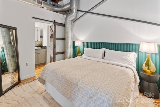 bedroom featuring light hardwood / wood-style floors and ensuite bath