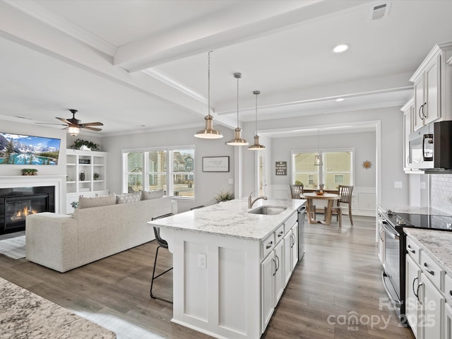 kitchen with sink, stainless steel appliances, an island with sink, and white cabinets