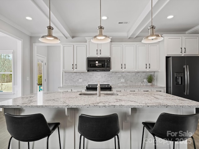 kitchen with white cabinetry, an island with sink, and sink