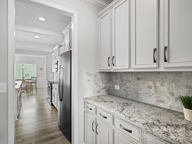 kitchen with appliances with stainless steel finishes, white cabinetry, crown molding, light stone countertops, and dark wood-type flooring