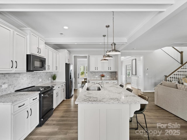 kitchen featuring sink, white cabinetry, decorative light fixtures, an island with sink, and black appliances