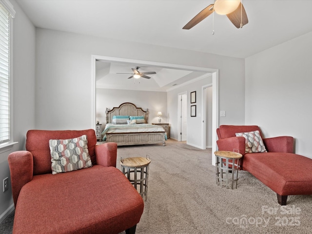 carpeted bedroom with multiple windows, a tray ceiling, and ceiling fan