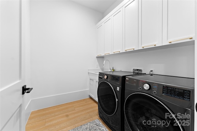 laundry room featuring cabinets, separate washer and dryer, light wood-type flooring, and sink