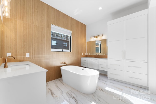 bathroom featuring a bathtub, vanity, and wooden walls