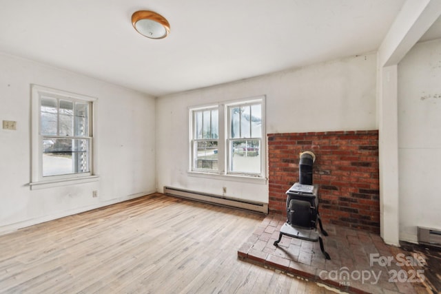 living room featuring baseboard heating, a wood stove, and light wood-type flooring