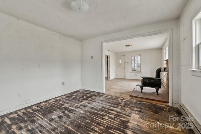 interior space featuring a wood stove, dark hardwood / wood-style flooring, and a baseboard heating unit