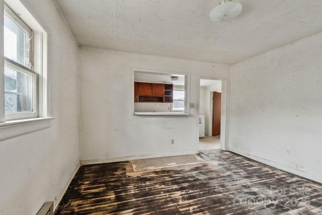 empty room featuring wood-type flooring and a baseboard heating unit