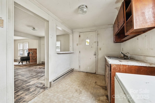 kitchen with sink, a wood stove, and baseboard heating