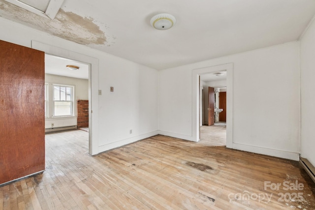 empty room featuring a baseboard radiator and light hardwood / wood-style floors