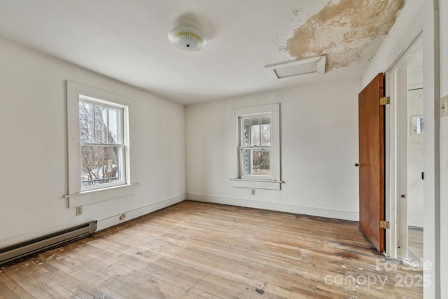 empty room featuring light wood-type flooring and a baseboard heating unit