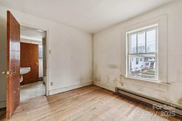 unfurnished room featuring light hardwood / wood-style floors and a baseboard heating unit