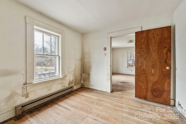 empty room with light hardwood / wood-style floors and a baseboard heating unit