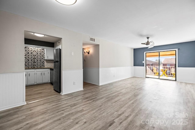 empty room with ceiling fan and light hardwood / wood-style floors