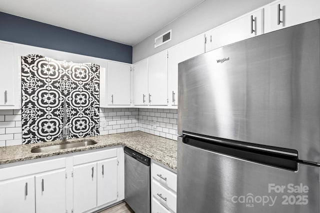 kitchen with backsplash, stainless steel appliances, light stone counters, and white cabinets