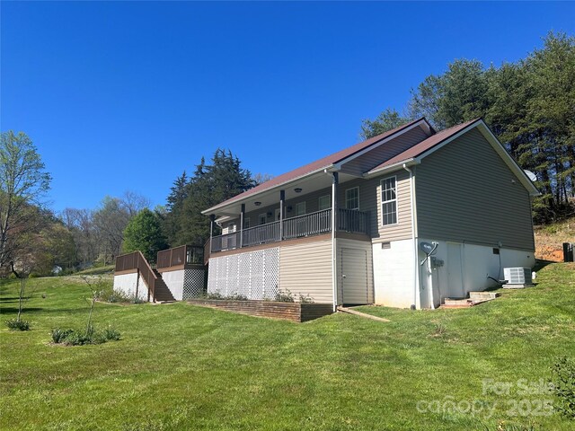 rear view of property with central air condition unit, stairs, and a lawn
