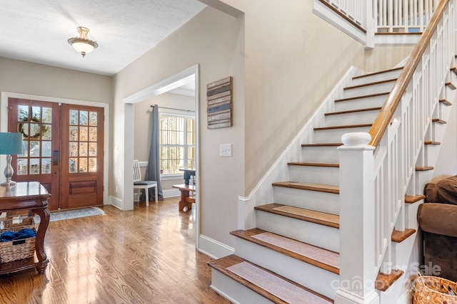 foyer entrance with french doors, a textured ceiling, a wealth of natural light, and hardwood / wood-style flooring