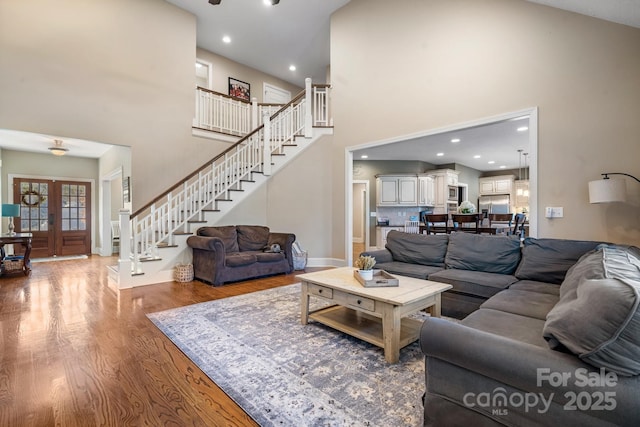 living room featuring a towering ceiling, wood-type flooring, and french doors