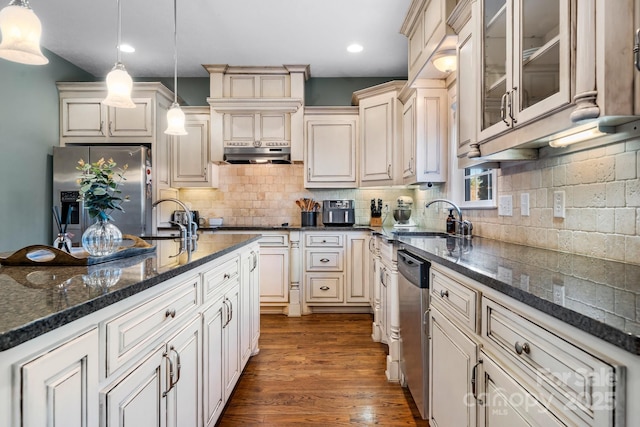 kitchen featuring appliances with stainless steel finishes, decorative light fixtures, sink, and tasteful backsplash