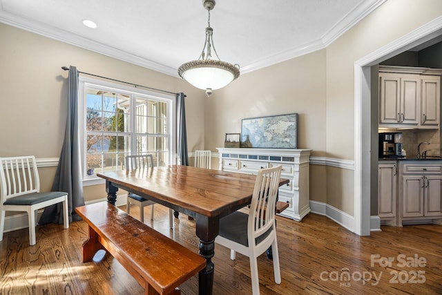 dining room featuring sink, ornamental molding, and dark hardwood / wood-style floors