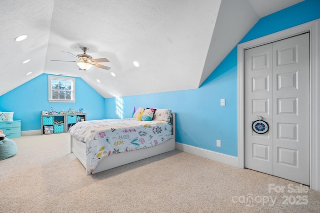 carpeted bedroom featuring ceiling fan, vaulted ceiling, a closet, and a textured ceiling