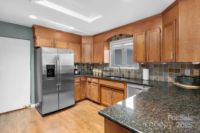 kitchen featuring stainless steel fridge, backsplash, dark stone countertops, dishwasher, and sink