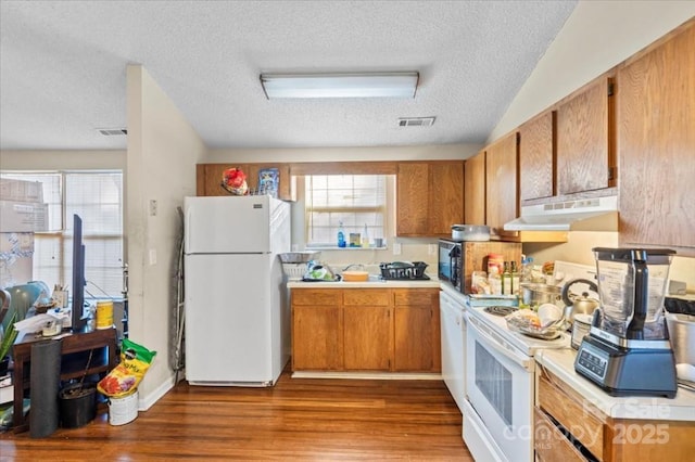 kitchen with a textured ceiling, a wealth of natural light, light hardwood / wood-style floors, and white appliances