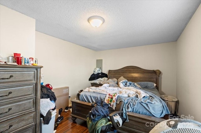 bedroom featuring a textured ceiling and dark hardwood / wood-style flooring