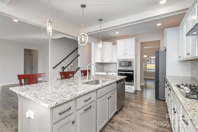 kitchen with sink, backsplash, an island with sink, stainless steel appliances, and white cabinets