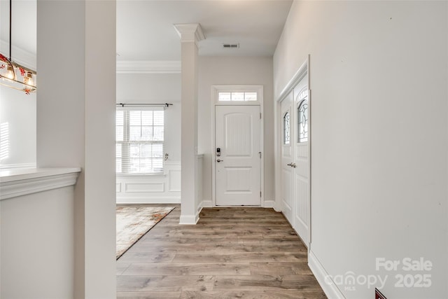 entrance foyer featuring ornamental molding and light hardwood / wood-style floors