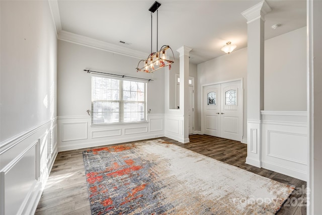 foyer entrance featuring decorative columns, ornamental molding, and hardwood / wood-style floors