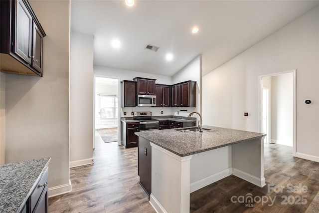 kitchen with vaulted ceiling, stainless steel appliances, dark hardwood / wood-style floors, sink, and dark brown cabinets