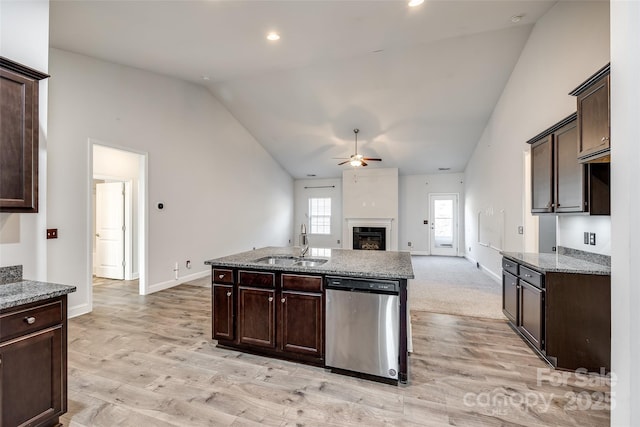 kitchen with light stone counters, dark brown cabinetry, sink, stainless steel dishwasher, and lofted ceiling