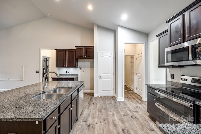 kitchen featuring a kitchen island with sink, stainless steel appliances, light wood-type flooring, sink, and lofted ceiling