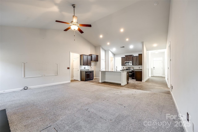 unfurnished living room with ceiling fan, light colored carpet, high vaulted ceiling, and sink