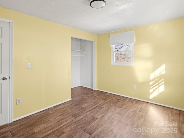 unfurnished bedroom with a closet, a textured ceiling, and hardwood / wood-style floors