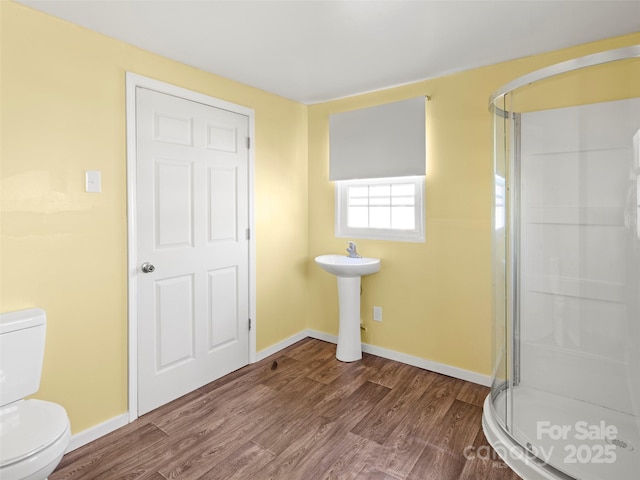 bathroom featuring sink, wood-type flooring, toilet, and a shower with door