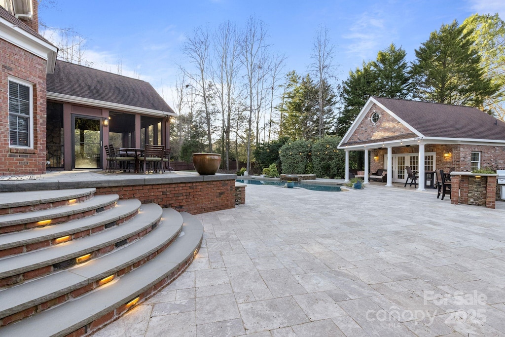 view of patio / terrace with an outdoor structure and a pool with hot tub