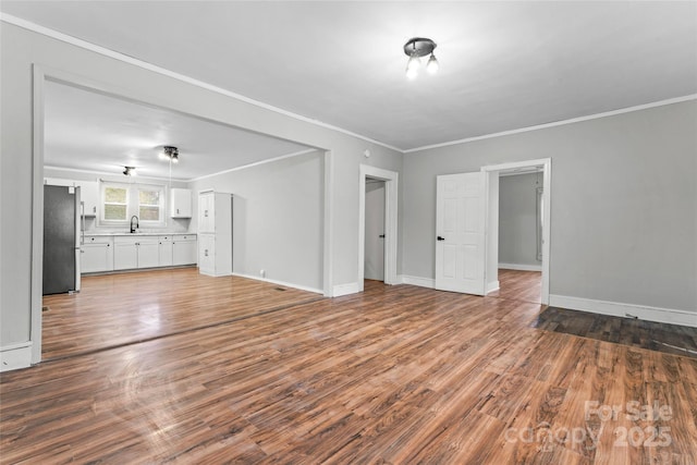 unfurnished living room featuring crown molding, sink, and hardwood / wood-style floors