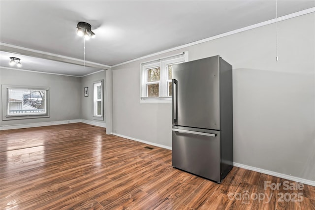 interior space featuring stainless steel fridge, dark wood-type flooring, ornamental molding, and a healthy amount of sunlight