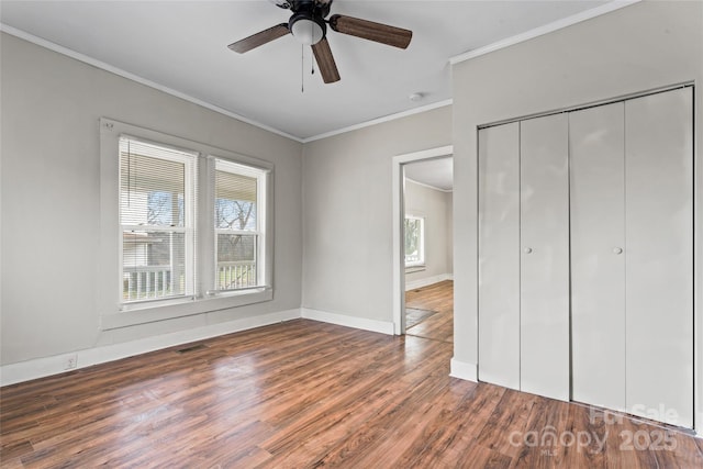 unfurnished bedroom with ceiling fan, dark hardwood / wood-style flooring, ornamental molding, and a closet