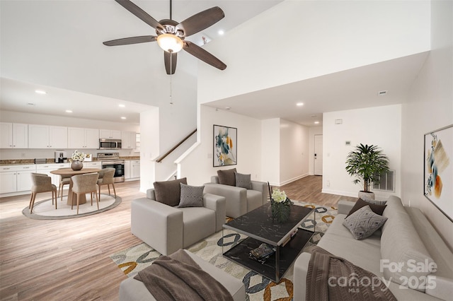 living room featuring light wood-type flooring, ceiling fan, and high vaulted ceiling