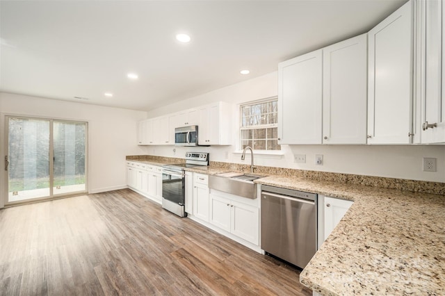 kitchen featuring stainless steel appliances, white cabinetry, and light stone countertops