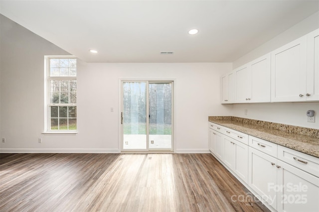 kitchen featuring light hardwood / wood-style floors, white cabinets, and light stone countertops