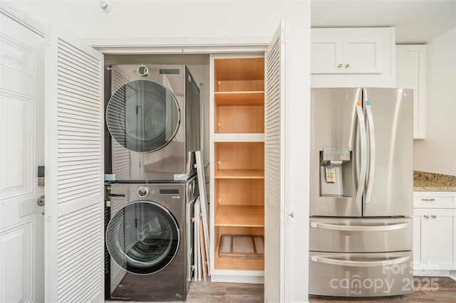 laundry room featuring dark wood-type flooring and stacked washing maching and dryer