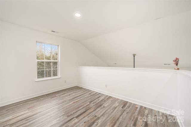 additional living space with vaulted ceiling and light hardwood / wood-style flooring